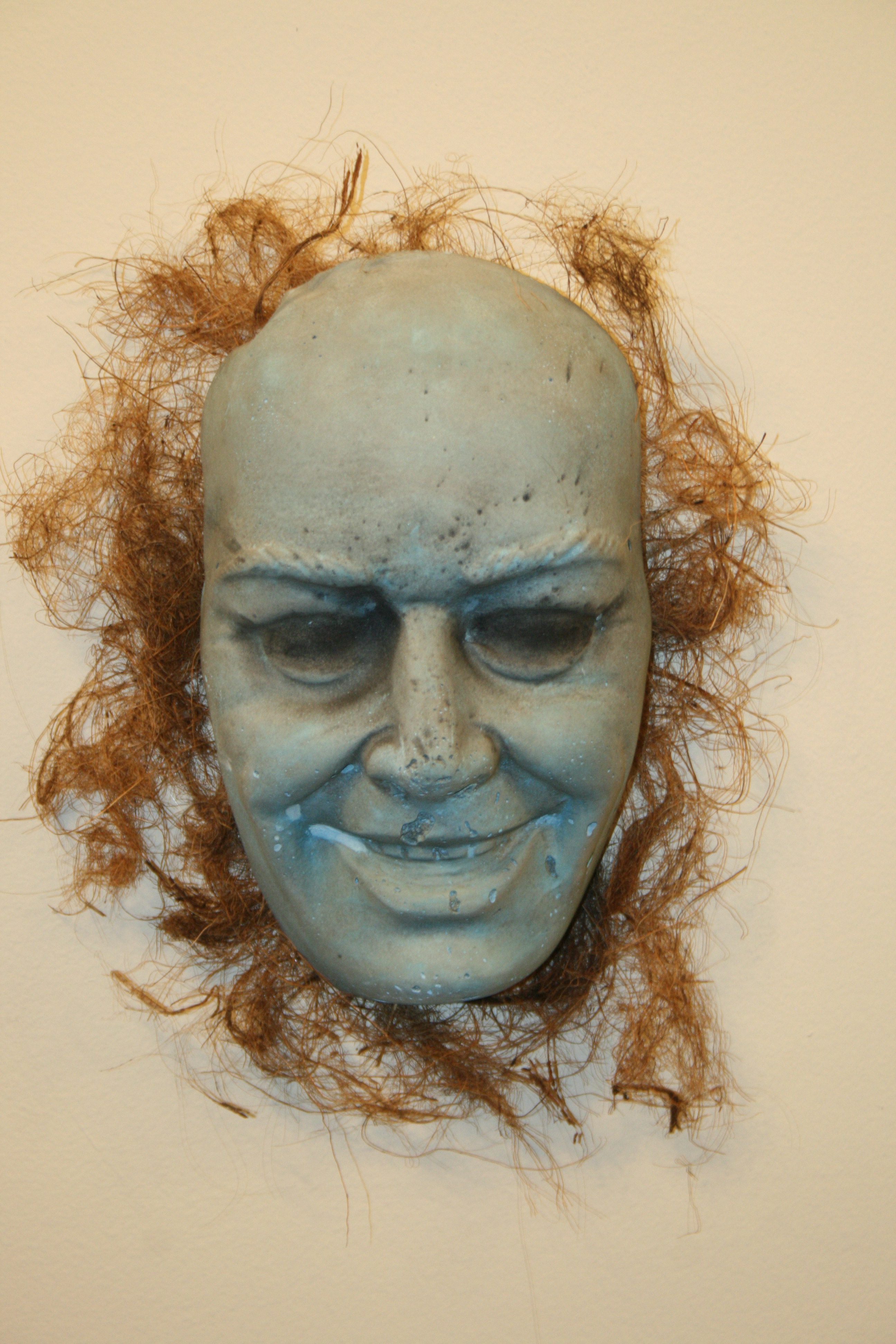 Hairy blue man concrete face wall sculpture