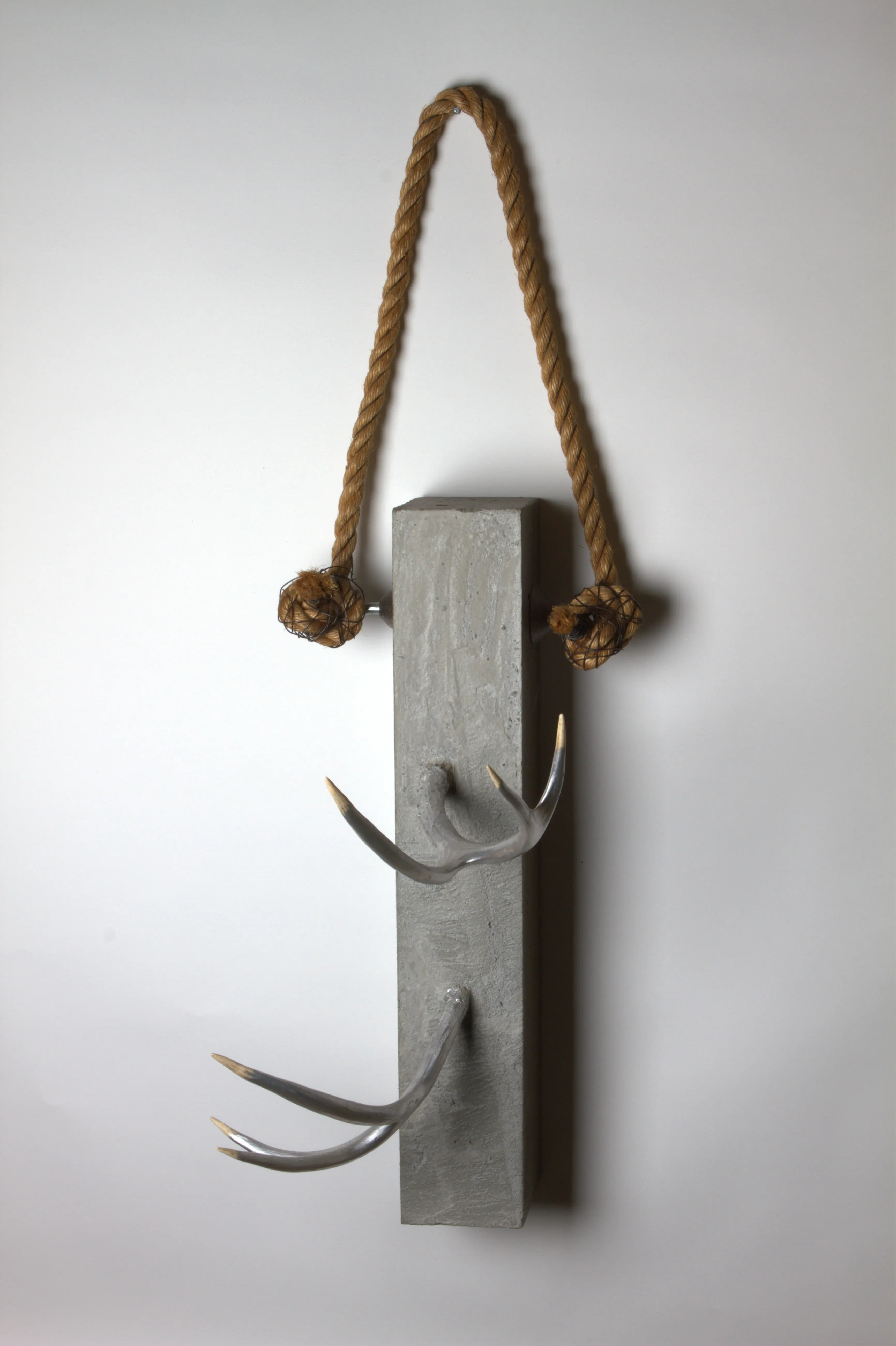 Horns breaking out of concrete monolith wall sculpture
